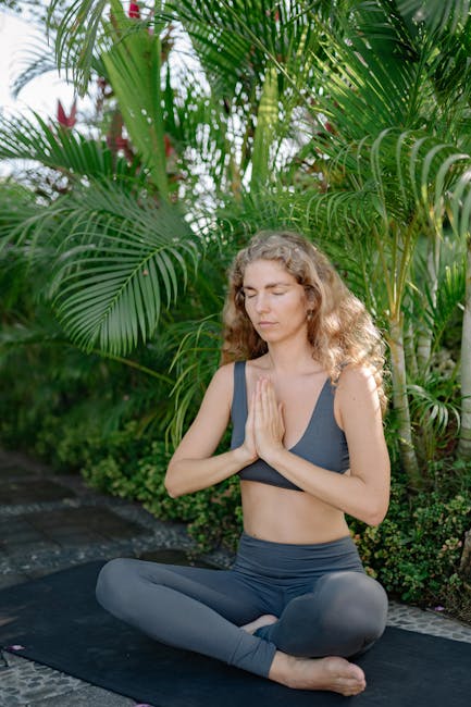 A person in a calm state of mind, meditating outdoors surrounded by lush greenery.