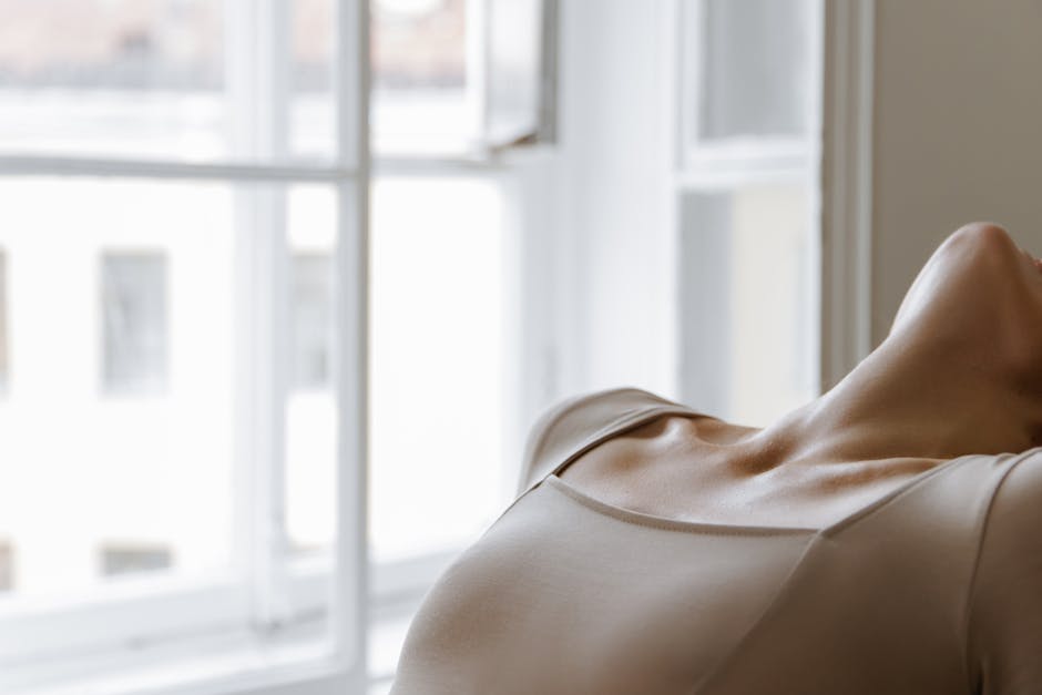 Woman performing a gentle yoga pose in a beautifully lit room with soft morning light.